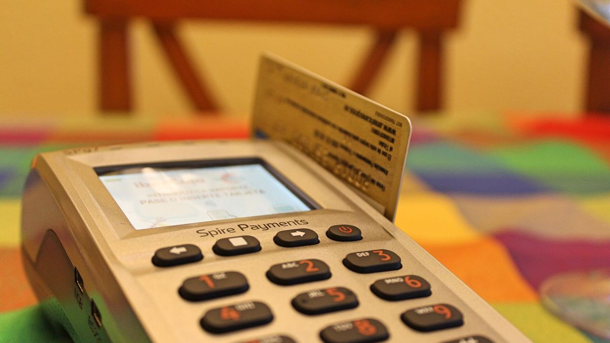 Bankkarte neben einem Stapel Casino-Chips und einem Smartphone auf einem dunklen Holztisch