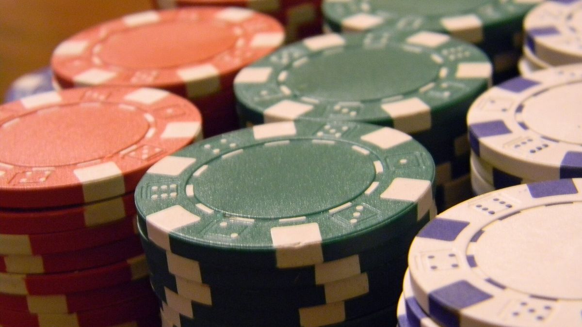 Laptop mit leerem Bildschirm neben einem hohen Stapel Casino-Chips und einem Taschenrechner