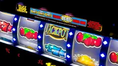 Nahaufnahme einer Spielautomaten-Walze neben einem Haufen goldfarbener Spielmarken