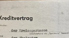 Quittung ohne lesbaren Text neben Taschenrechner, Casino-Chips und zugeklapptem Laptop auf einem Eichentisch